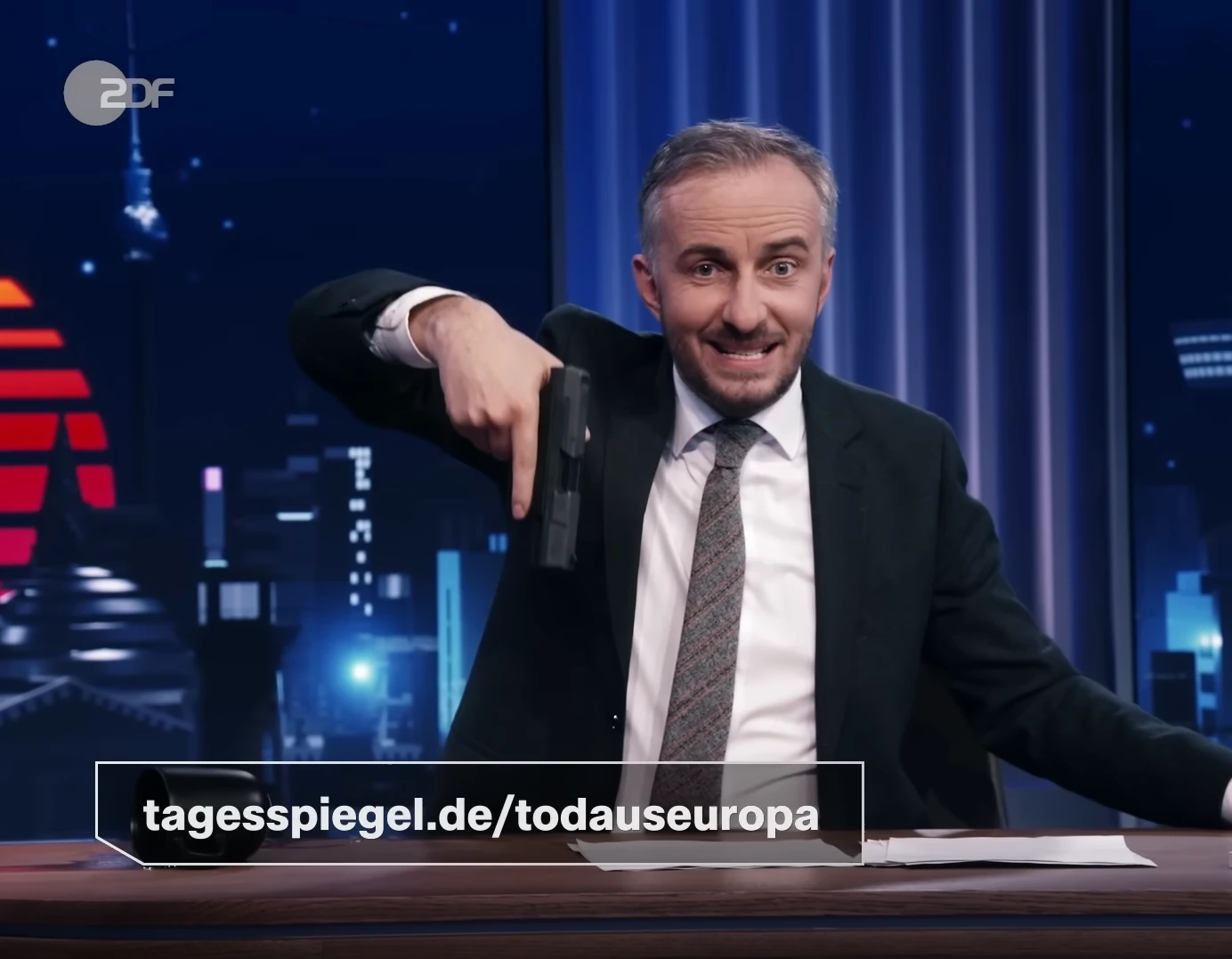 Screenshot from ZDF Magazin Royale TV showing host Jan Böhermann holding a gun